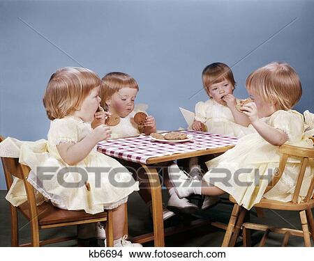 1960S Quadruplicate Baby Girls Sitting At Table Eating Cookies View Large Photo Image Picture - 1960S Quadruplicate Baby Girls Sitting At Table Eating Cookies. Fotosearch