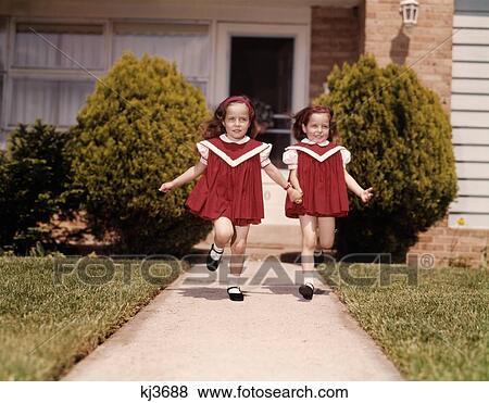 1960S Twin Girls Wearing Identical Red Dresses Holding Hands Running Down Sidewalk Of Suburban House Looking At Camera View Large Photo Image Stock Photo - 1960S Twin Girls Wearing Identical Red Dresses Holding Hands Running Down Sidewalk Of Suburban House Looking At Camera. Fotosearch