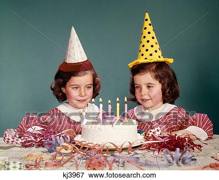 Stock Photo - 1960S Twin Girls Wearing Party Hats And Birthday Cake With Five Candles . Fotosearch