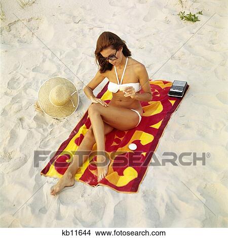 1960S Woman Applying Suntan Sun Screen Lotion Sitting On Beach Towel View Large Photo Image Picture - 1960S Woman Applying Suntan Sun Screen Lotion Sitting On Beach Towel. Fotosearch