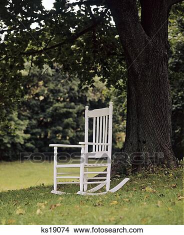 Picture - 1980S Solitary Single White Painted Rocking Chair Sitting Under Mature Tree. Fotosearch