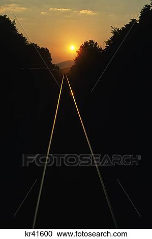 Stock Image - 1980S Sunrise Or Sunset Reflection On Railroad Track Rails Stretching To Horizon. Fotosearch