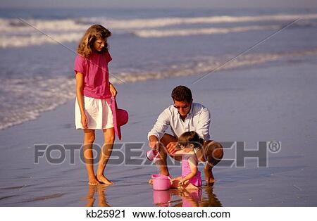 Stock Image - 1980S Young Family Of Three At Beach. Fotosearch