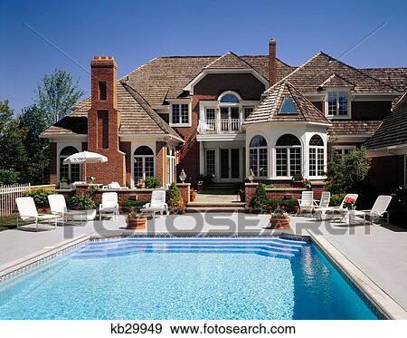 Stock Photo - Luxurious Suburban Home With Swimming Pool White Lounge Chairs. Fotosearch