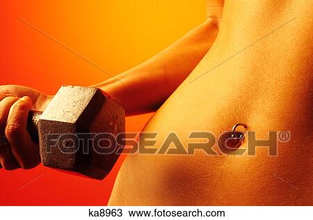 Stock Image - Woman Torso With Pierced Bellybutton Curling Hand Weight Close-Up. Fotosearch