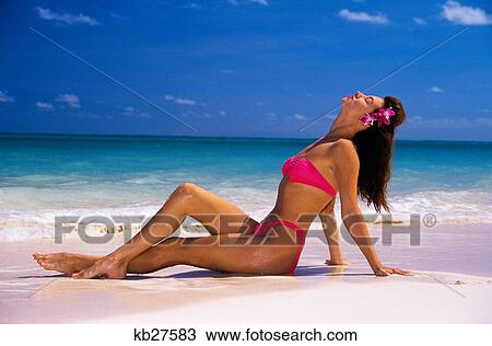 Stock Image - Young Woman Sitting Reclining In Profile On Sand At Ocean's Edge. Fotosearch