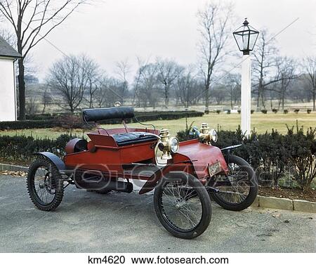 Stock Image - 1900S 1910S Antique Horseless Carriage Red With Wire Spoke Bicycle Wheels. Fotosearch