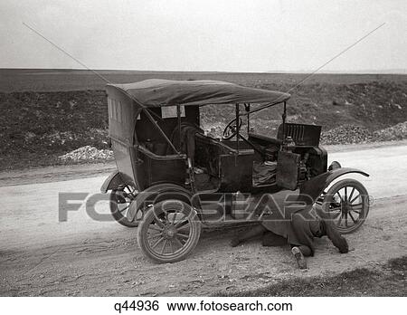 1920S Man On His Hands And Knees Looking Under Model T Broken Down On Roadside View Large Photo Image Stock Photograph - 1920S Man On His Hands And Knees Looking Under Model T Broken Down On Roadside . Fotosearch