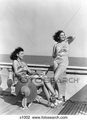 1930S 1940S Two Women Sitting On Hotel Deck Beach Side In One Piece Bathing Suit Fashion Florida Usa View Large Photo Image Stock Image - 1930S 1940S Two Women Sitting On Hotel Deck Beach Side In One Piece Bathing Suit Fashion Florida Usa. Fotosearch