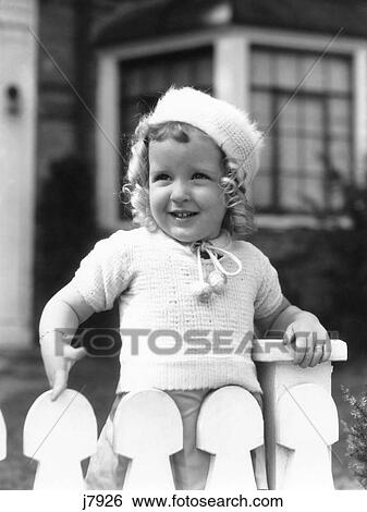 1930S Girl Toddler Wooden Picket Fence Wearing Knit Sweater & Hat Blond Curls View Large Photo Image Stock Photograph - 1930S Girl Toddler Wooden Picket Fence Wearing Knit Sweater & Hat Blond Curls. Fotosearch