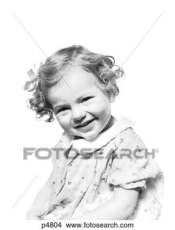 1930s Smiling Toddler Girl Short Curly Hair With Bow Wearing Print