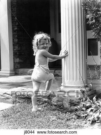 1930S Smiling Toddler Girl Stepping Up Onto Porch Touching Column Summer Blond Curly Hair House Lawn View Large Photo Image Picture - 1930S Smiling Toddler Girl Stepping Up Onto Porch Touching Column Summer Blond Curly Hair House Lawn. Fotosearch