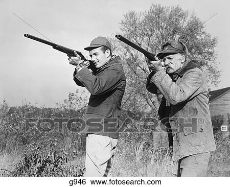 1940S 1950S Men Young Senior With Shot Guns Aiming Towards Camera Wearing Hunting Clothes & Hats View Large Photo Image Stock Photograph - 1940S 1950S Men Young Senior With Shot Guns Aiming Towards Camera Wearing Hunting Clothes & Hats . Fotosearch