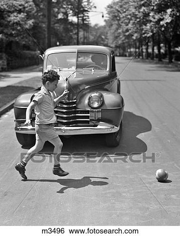 1940S Boy Running After Ball Into Street Oblivious To Oncoming Car About To Hit Him View Large Photo Image Stock Photograph - 1940S Boy Running After Ball Into Street Oblivious To Oncoming Car About To Hit Him . Fotosearch