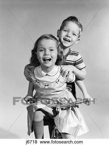 1950S Girl Wearing A Dress With Riding A Tricycle While A Boy Is Standing On Back Holding On To Her Shoulders View Large Photo Image Stock Photo - 1950S Girl Wearing A Dress With Riding A Tricycle While A Boy Is Standing On Back Holding On To Her Shoulders. Fotosearch