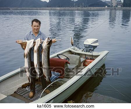 1960s 漁師 地位 中に 小さい 船外ﾓｰﾀｰﾎﾞｰﾄ カメラを見る 持ちこたえる その日のキャッチ ３ 大きい Muskies ストックフォト 写真素材 Ka1605 Fotosearch