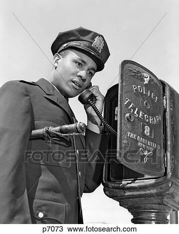 1960S African American Police Officer Making Call At Police Box Telephone Night Stick Tucked Under His Arm View Large Photo Image Stock Image - 1960S African American Police Officer Making Call At Police Box Telephone Night Stick Tucked Under His Arm . Fotosearch