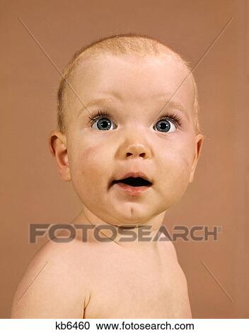 Stock Image - 1960S Baby Portrait Wide Eyed Wonder Facial Expression Looking At Camera. Fotosearch