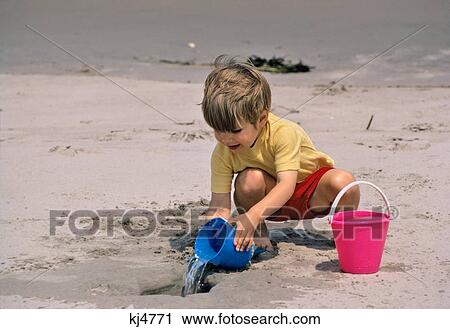 Stock Image - 1960S Little Boy Playing In Sand At Beach . Fotosearch
