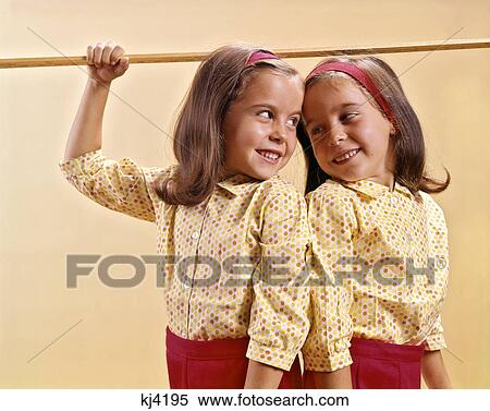 1960S Twin Girls Measuring Their Height With Ruler Across Top Of Their Heads View Large Photo Image Stock Photography - 1960S Twin Girls Measuring Their Height With Ruler Across Top Of Their Heads. Fotosearch