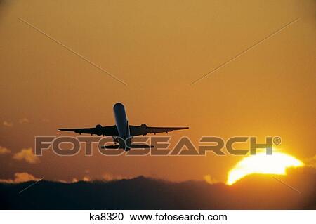Stock Image - 757 Airplane Jet Takeoff Into Sunset. Fotosearch