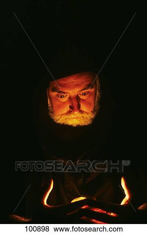 Stock Photo - Character Man Wizard Or Fortune Teller Looking Down Into Eerie Light. Fotosearch