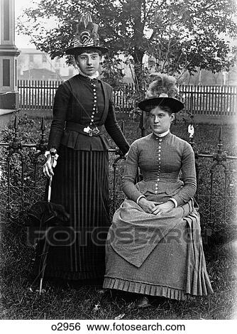 1880s 1890s PORTRAIT TWO WOMEN IN STYLISH CLOTHES WEARING HATS IN FRONT LAWN POSED LOOKING AT CAMERA View Large Photo Image Stock Photograph - 1880s 1890s PORTRAIT TWO WOMEN IN STYLISH CLOTHES WEARING HATS IN FRONT LAWN POSED LOOKING AT CAMERA. Fotosearch