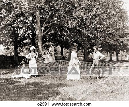 1890s 1900s GROUP OF MEN AND WOMEN GATHERED AROUND GRASS TENNIS COURT HOLDING RACQUETS View Large Photo Image Stock Image - 1890s 1900s GROUP OF MEN AND WOMEN GATHERED AROUND GRASS TENNIS COURT HOLDING RACQUETS. Fotosearch