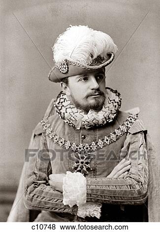 Stock Photo - 1890s MAN ACTOR IN ELIZABETHAN FASHION COSTUME RUFFLED COLLAR & CUFFS VELVET TUNIC HAT WITH LARGE FEATHER PLUME & BEARD. Fotosearch