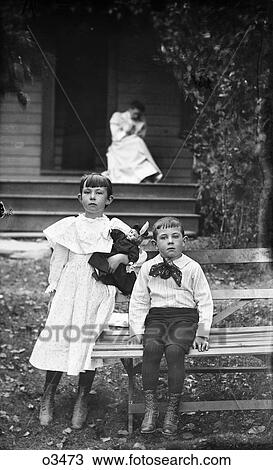 1900S Portrait Boy Girl Posing Sitting On Bench In Front Of House Looking At Camera Woman In Background On Porch View Large Photo Image Stock Image - 1900S Portrait Boy Girl Posing Sitting On Bench In Front Of House Looking At Camera Woman In Background On Porch. Fotosearch