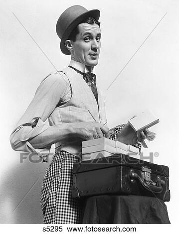 1910S 1920S Character Con Man Barker Salesman Wearing Bowler Hat Looking At Camera Selling Product Out Of Small Suitcase View Large Photo Image Stock Photography - 1910S 1920S Character Con Man Barker Salesman Wearing Bowler Hat Looking At Camera Selling Product Out Of Small Suitcase . Fotosearch