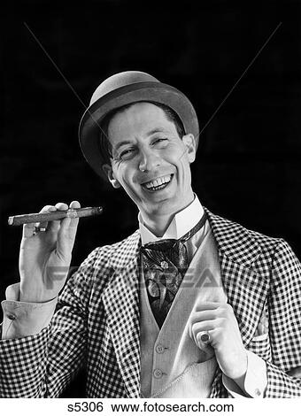 1910S 1920S Portrait Smiling Character Con Man Bowler Hat Fancy Suit Cravat Smoking Cigar Looking At Camera View Large Photo Image Stock Photograph - 1910S 1920S Portrait Smiling Character Con Man Bowler Hat Fancy Suit Cravat Smoking Cigar Looking At Camera . Fotosearch
