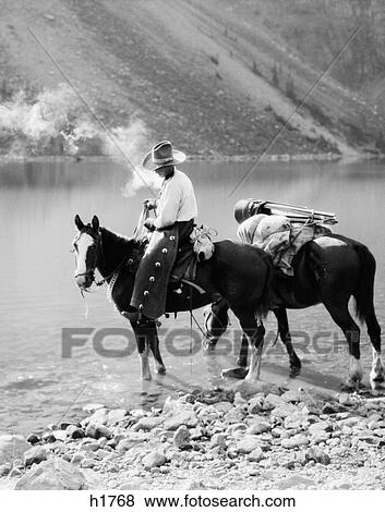 1920S 1930S Man Cowboy On Horse With Pack Horse By Moraine Lake Alberta Canada View Large Photo Image Stock Photo - 1920S 1930S Man Cowboy On Horse With Pack Horse By Moraine Lake Alberta Canada . Fotosearch