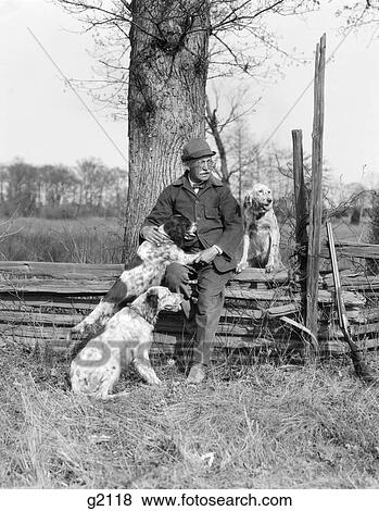 1920S 1930S Senior Man Hunting Clothes Sitting Spit Rail Fence With Three English Setter Dogs View Large Photo Image Stock Photo - 1920S 1930S Senior Man Hunting Clothes Sitting Spit Rail Fence With Three English Setter Dogs. Fotosearch