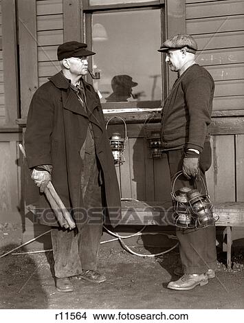1920s 1930s TWO RAILROAD WORKERS HOLDING LANTERNS & FLAGS A FLAGMAN CONDUCTOR AND A BRAKEMAN MEETING AND TALKING View Large Photo Image Picture - 1920s 1930s TWO RAILROAD WORKERS HOLDING LANTERNS & FLAGS A FLAGMAN CONDUCTOR AND A BRAKEMAN MEETING AND TALKING. Fotosearch