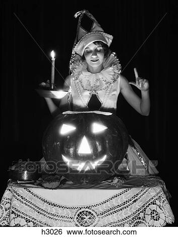 1920S 1930S Woman In Harlequin Costume Holding Candle Looking Down Into Carved Pumpkin Jack-O-Lantern View Large Photo Image Stock Photograph - 1920S 1930S Woman In Harlequin Costume Holding Candle Looking Down Into Carved Pumpkin Jack-O-Lantern. Fotosearch