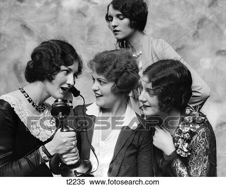 1920s GROUP OF LADIES LISTENING IN ON ANOTHER WOMAN TALKING ON A CANDLESTICK TELEPHONE View Large Photo Image Stock Photography - 1920s GROUP OF LADIES LISTENING IN ON ANOTHER WOMAN TALKING ON A CANDLESTICK TELEPHONE. Fotosearch