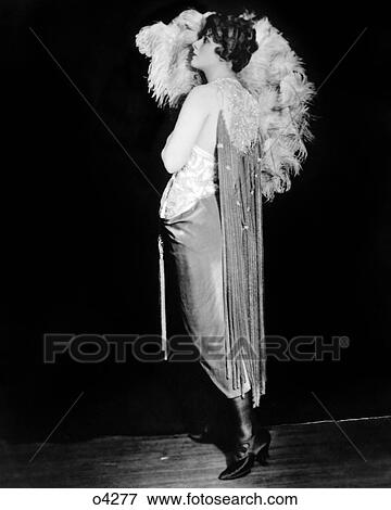 Stock Photo - 1920s MARGARET IRVING OF 1920 ZIEGFELD FOLLIES WOMAN PROFILE EVENING GOWN FEATHER FAN NEW YORK CITY USA. Fotosearch