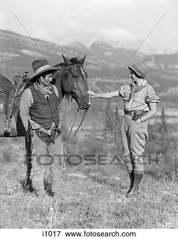 1920S Outdoor Woman Talking With Native American Stoney Sioux Indian Western Trail Guide Man And His Horse Alberta Canada View Large Photo Image Stock Photo - 1920S Outdoor Woman Talking With Native American Stoney Sioux Indian Western Trail Guide Man And His Horse Alberta Canada . Fotosearch