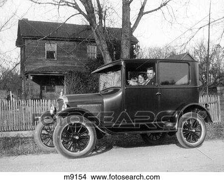 1920s SIDE VIEW OF FAMILY IN MODEL T FORD PARKED IN FRONT OF RURAL HOME WITH FENCE LOOKING AT CAMERA View Large Photo Image Picture - 1920s SIDE VIEW OF FAMILY IN MODEL T FORD PARKED IN FRONT OF RURAL HOME WITH FENCE LOOKING AT CAMERA. Fotosearch