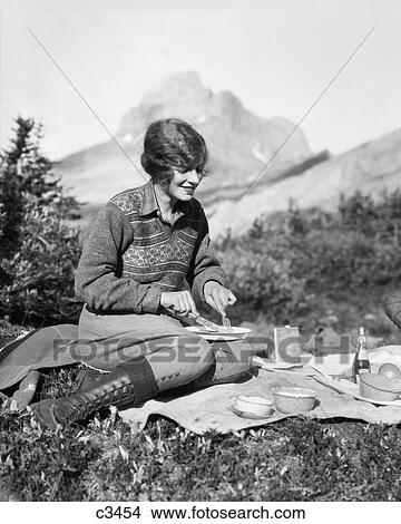 1920S Woman Camping Eating Breakfast Outdoors Sitting On Grass Mountains In Background Baker Lake Alberta Canada View Large Photo Image Picture - 1920S Woman Camping Eating Breakfast Outdoors Sitting On Grass Mountains In Background Baker Lake Alberta Canada. Fotosearch