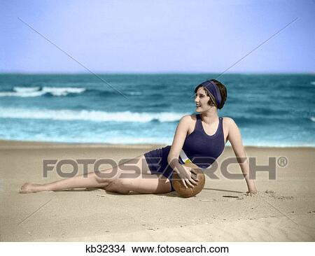 1920S Woman In Bathing Suit Stretched Out On Beach In Front Of Water Holding Ball View Large Photo Image Picture - 1920S Woman In Bathing Suit Stretched Out On Beach In Front Of Water Holding Ball. Fotosearch