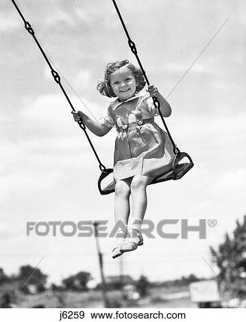 1930s 1940s SMILING GIRL ON SWING OUTDOOR LOOKING AT CAMERA View Large Photo Image Stock Photo - 1930s 1940s SMILING GIRL ON SWING OUTDOOR LOOKING AT CAMERA. Fotosearch