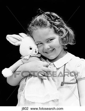 1930s 1940s SMILING YOUNG GIRL LOOKING AT CAMERA HOLDING HUGGING STUFFED RABBIT TOY ANIMAL View Large Photo Image Stock Image - 1930s 1940s SMILING YOUNG GIRL LOOKING AT CAMERA HOLDING HUGGING STUFFED RABBIT TOY ANIMAL. Fotosearch