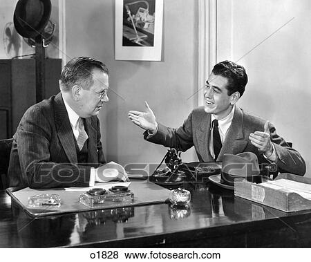 1930s 1940s TWO MEN SEATED AT DESK YOUNGER MAN TALKING GESTURING ARMS UP OLDER MAN LISTENS View Large Photo Image Stock Photo - 1930s 1940s TWO MEN SEATED AT DESK YOUNGER MAN TALKING GESTURING ARMS UP OLDER MAN LISTENS. Fotosearch