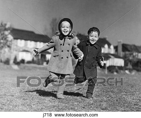 1930s BOY GIRL WEARING WINTER COATS HATS RUNNING IN GRASS LOOKING AT CAMERA View Large Photo Image Stock Photo - 1930s BOY GIRL WEARING WINTER COATS HATS RUNNING IN GRASS LOOKING AT CAMERA. Fotosearch