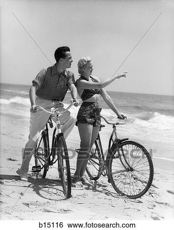 1930S Couple Man Woman Biking On Beach Woman Pointing To Horizon View Large Photo Image Stock Photograph - 1930S Couple Man Woman Biking On Beach Woman Pointing To Horizon. Fotosearch