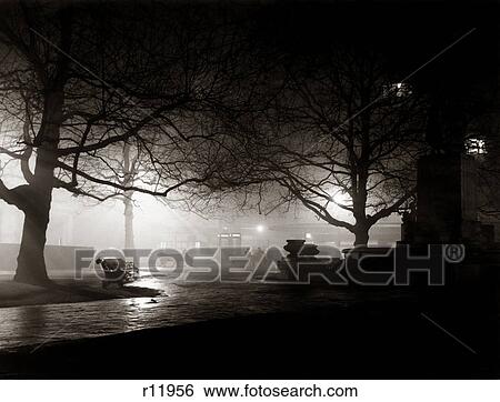 Stock Photograph - 1930s DARK SPOOKY EERIE PARK BENCHES LEICESTER SQUARE LONDON ENGLAND. Fotosearch