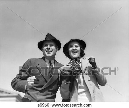 1930s EXCITED HAPPY SPECTATOR COUPLE OUTDOORS CHEERING View Large Photo Image Stock Image - 1930s EXCITED HAPPY SPECTATOR COUPLE OUTDOORS CHEERING. Fotosearch