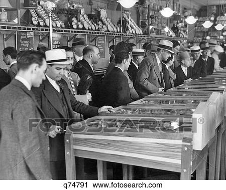 1930s GROUP MEN WEARING HATS PLAYING MARBLE PINBALL MACHINES IN BROADWAY AMUSEMENT ARCADE TIMES SQUARE NEW YORK CITY USA View Large Photo Image Stock Image - 1930s GROUP MEN WEARING HATS PLAYING MARBLE PINBALL MACHINES IN BROADWAY AMUSEMENT ARCADE TIMES SQUARE NEW YORK CITY USA. Fotosearch